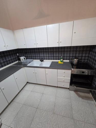 a kitchen with white cabinets and a sink and a stove at iraklitsa house in Iraklitsa