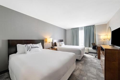 a hotel room with two beds and a flat screen tv at Home Inn and Suites Lloydminster in Lloydminster