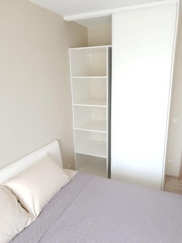a white bedroom with a bed and a closet at Ezerkrasts Kempes 28 in Liepāja