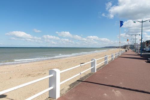 une plage avec une clôture blanche et l'océan dans l'établissement Le temps d'une pause, à Villers-sur-Mer