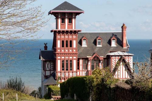 une grande maison avec une tour au sommet de l'océan dans l'établissement Le temps d'une pause, à Villers-sur-Mer