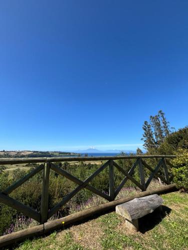 a wooden fence on top of a hill with flowers at Cabañas Vista Volcanes del Sur in Llanquihue