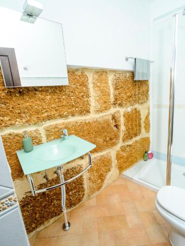 a bathroom with a sink and a stone wall at Puerta Romana in Carmona