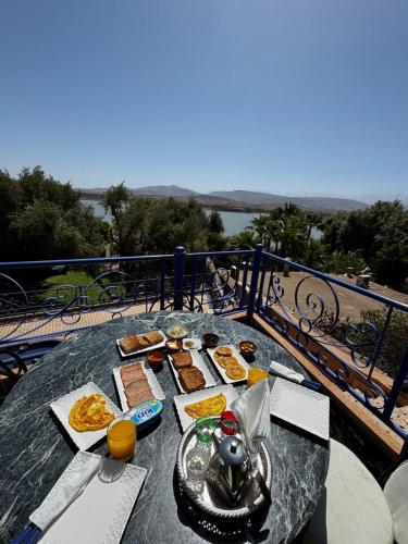 a table with food on top of a balcony at Dar NFis Suites et chambres de luxe dans un havre de paix vue paradisiaque au bord du lac in Lalla Takerkoust