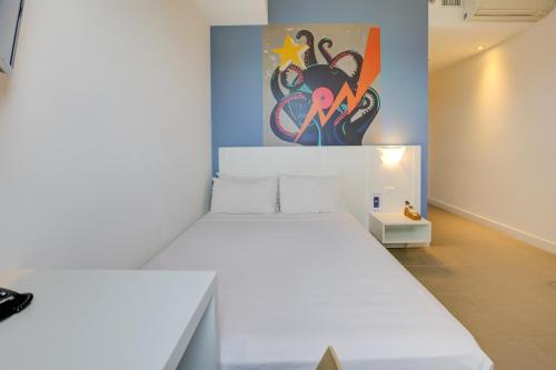 a bedroom with a white bed and a painting on the wall at Transamerica Fit Jacareí in Jacareí