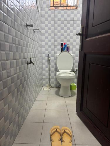 a bathroom with a toilet and a pair of shoes at Bukoto Kampala Kickoff Ntinda Luxury apartment in Kampala