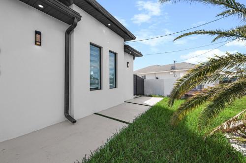a white house with a sidewalk and palm trees at Luxury Apartment to Relax in Cape Coral