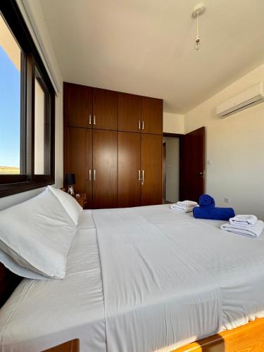 a bedroom with a large white bed with wooden cabinets at Lazuli Zen Villa with Private Pool in Pyla