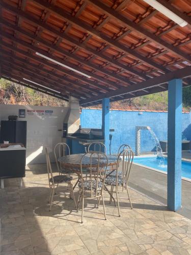 eine Terrasse mit Tisch und Stühlen und einem Pool in der Unterkunft sitio sonho verde in Serra Negra