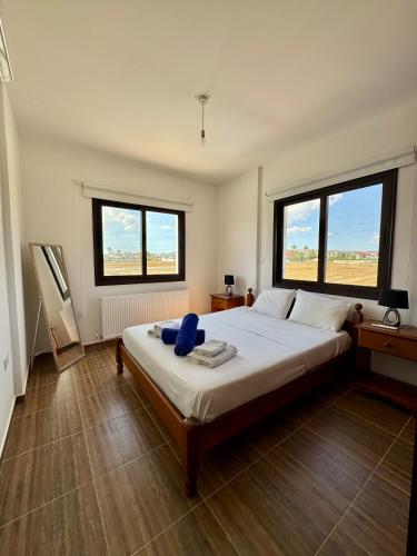 a bedroom with a large bed with two windows at Lazuli Zen Villa with Private Pool in Pyla