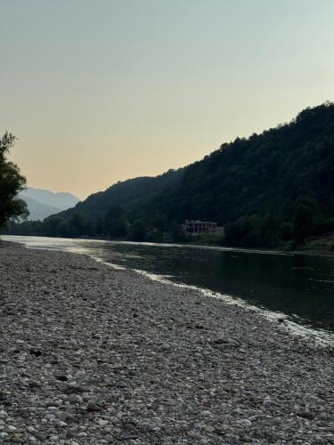 a river with a rocky shore with trees in the background at Apartman Drinsko Srce in Bratunac