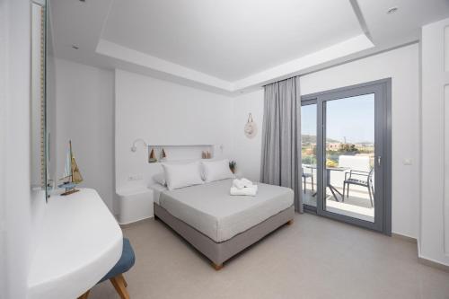 a white bedroom with a bed and a balcony at calmare collection hotel in Plaka
