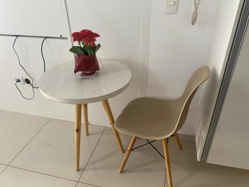 a table and a chair with a vase of flowers on it at Df Plaza Flat, Excelente in Águas Claras