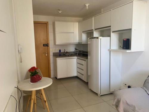 a kitchen with white cabinets and a table and a refrigerator at Df Plaza Flat, Excelente in Águas Claras