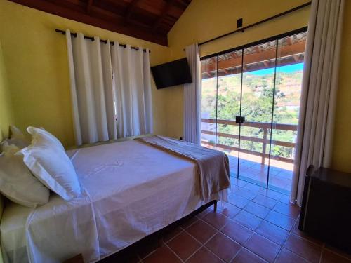 a bedroom with a bed and a large window at Chalé Davivi in Socorro