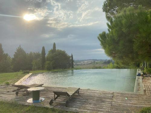 une terrasse en bois avec une table et des chaises à côté d'un lac dans l'établissement Le Chalet de la Gestère, à Ambax