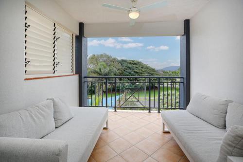 a living room with a couch and a balcony at Tropical Comfort Pool and Stunning Esplanade in Cairns