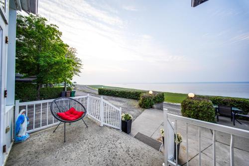a red chair sitting on a balcony overlooking the ocean at Le Repaire du Fleuve in Sainte-Croix