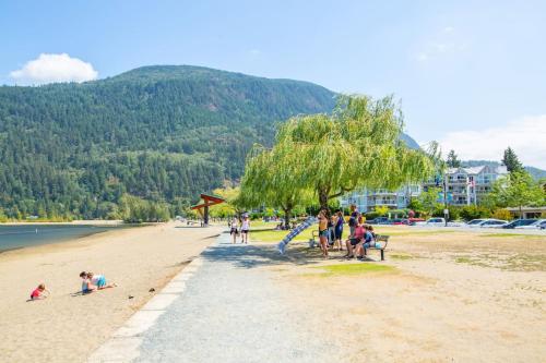 a group of people sitting on a beach at The Flats at Cedar Springs with Full Kitchen and Steps to Lake in Harrison Hot Springs