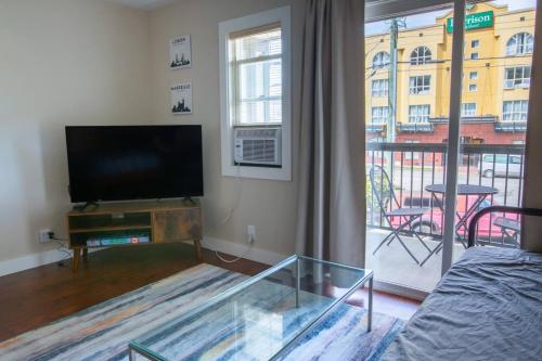 a living room with a flat screen tv and a balcony at Dogwood Suite 2 Beds and Walkable to Lake in Harrison Hot Springs