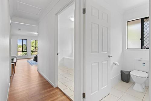 ブリスベンにあるSunnybank Hills Spacious 5BR Home for Familiesのトイレと窓のある白いバスルーム