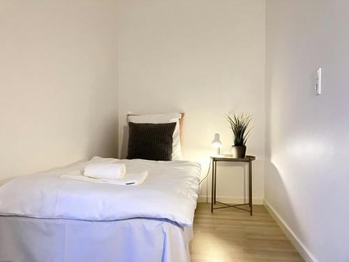ein kleines Schlafzimmer mit einem weißen Bett und einem Nachttisch in der Unterkunft Central Studio for 1 in Fredericia