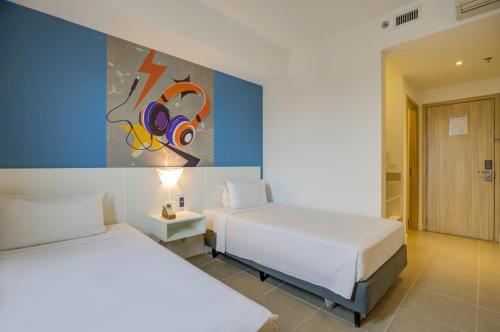 a bedroom with two beds and a painting on the wall at Transamerica Fit Jacareí in Jacareí