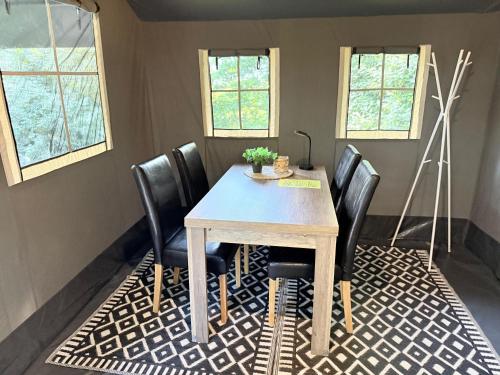 a dining room with a table and black chairs at Prachtige 4 persoons glampingtent op rustige kleine camping in Anna Paulowna
