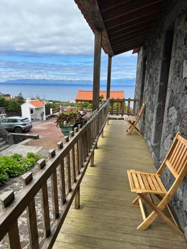 a wooden porch with a chair and the ocean at Sara Village in São Roque do Pico
