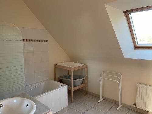 La salle de bains mansardée est pourvue d'une baignoire et d'un lavabo. dans l'établissement Maison avec jardin, proche plage, à Dinard