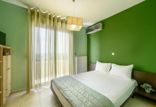 a green bedroom with a bed and a large window at Pentanemi Luxury Villa in Hanioti