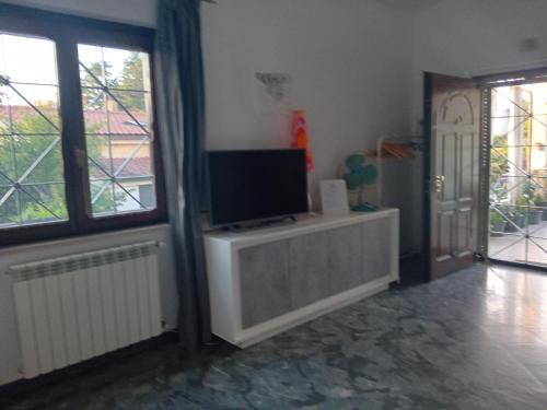 a living room with a tv on a cabinet and a door at Casa Bibi in Infernetto