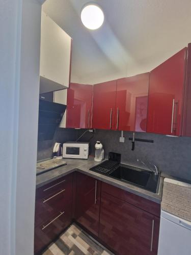 une cuisine avec des armoires rouges et un évier dans l'établissement Apartment T2 Gruissan, à Gruissan