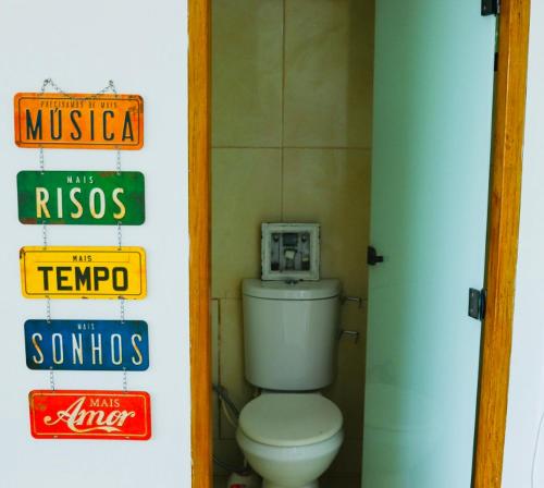 baño con aseo y carteles en la pared en Estância do Sol, en Pirenópolis
