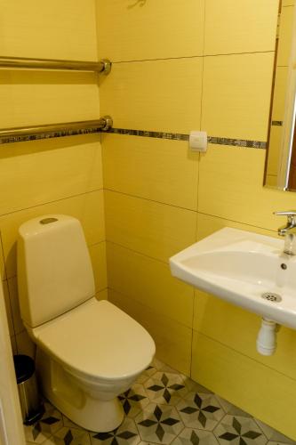 a yellow bathroom with a toilet and a sink at Blue Butterfly in Jūrmala