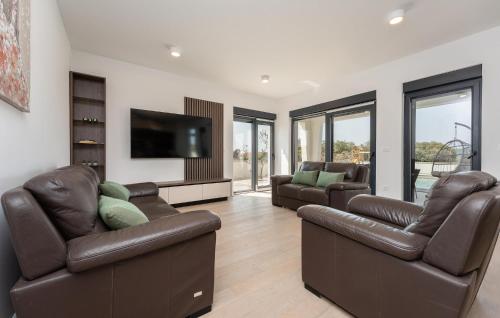 a living room with leather furniture and a flat screen tv at Cozy Home In Turanj With Sauna in Turanj