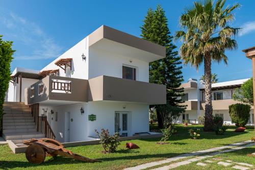 a white house with palm trees in the yard at Gaia Garden in Kos Town