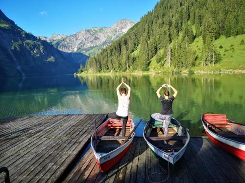 two people doing yoga on boats on a dock at Jungbrunn Der Gutzeitort in Tannheim