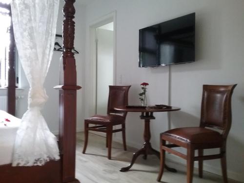 a room with a table and chairs and a tv at Hals Hotel in Hals