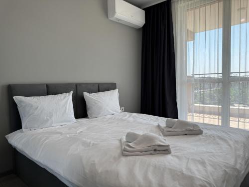 a bed with two towels on it with a window at 1BR Apartment with Panoramic View Balcony and Designated Parking Space in Plovdiv