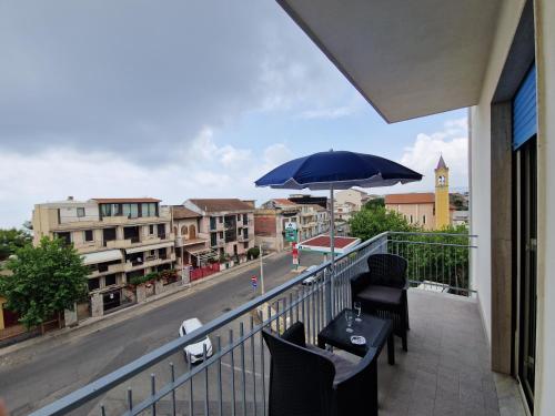 a balcony with chairs and an umbrella on a city street at Fondachello Suites - tra il vulcano e il Mar Ionio in Mascali