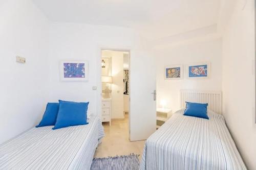 2 camas en una habitación blanca con almohadas azules en Modern Apartment in Marbella with Shared Pool, en Marbella