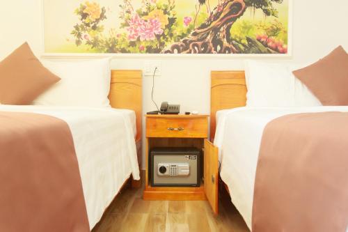 a room with two beds with a nightstand between them at Hopapa Hotel & Spa Phu Quoc in Phu Quoc
