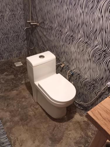 a toilet in a bathroom with a black and white wallpaper at Patience Airport cottages in Boma la Ngombe