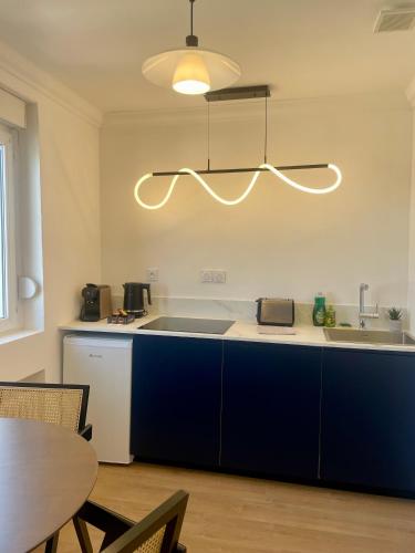 une cuisine avec des armoires bleues, une table et une lumière dans l'établissement Appartement Gare 2 Personnes, au Mans