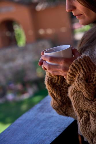 a woman holding a coffee cup in her hands at Piedra Wasi Ecolodge Urubamba in Urubamba