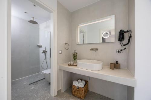 a white bathroom with a sink and a mirror at calmare collection hotel in Plaka