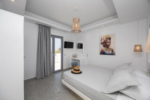 a white bedroom with a bed with a hat on it at calmare collection hotel in Plaka