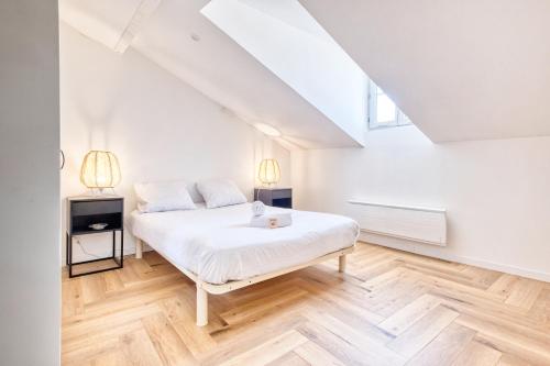 a bedroom with a white bed and wooden floors at la voliere de la Cathedrale in Périgueux