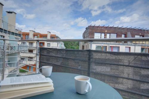 a table with a book and two cups of coffee on a balcony at HelApart - Foka in Hel
